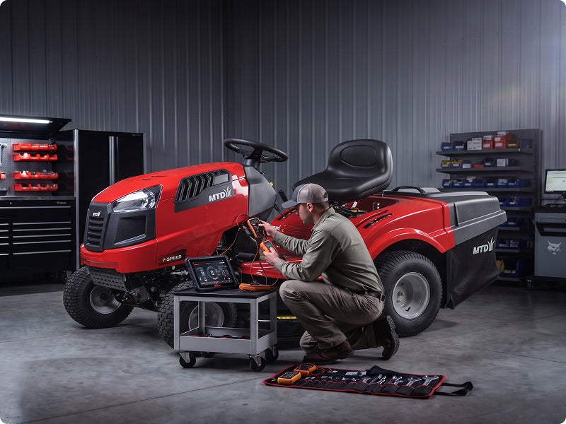 Technician performing diagnostics on a red tractor